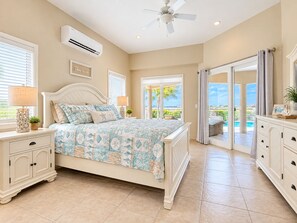 A bedroom with a bed, nightstands, a dresser, an air conditioning unit, and a ceiling fan. - Luxury Ocean View Villa, Stunning Views, 5 minutes to Beaches (Noord)
