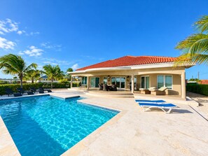 A poolside area with a house, lounge chairs, and a clear blue sky. - Luxury Ocean View Villa, Stunning Views, 5 minutes to Beaches (Noord)