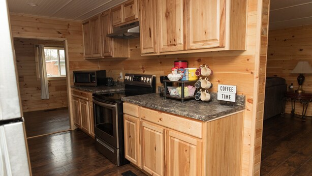 A kitchen with wooden cabinets, a microwave, an oven, and a coffee station.