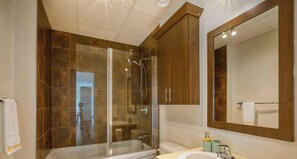 Une salle de bain moderne avec une douche à parois de verre, une baignoire, un grand miroir et des meubles en bois.