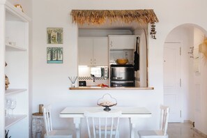 Une cuisine avec des meubles blancs, un four noir et une table à manger avec des chaises.
