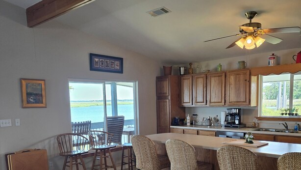 A spacious kitchen with wooden cabinets, a dining area with wicker chairs, and a view of the outdoors.