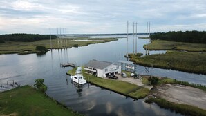 A house with a dock and a boat, surrounded by water and greenery.