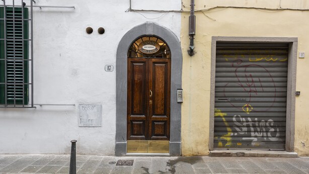A building with a wooden door and a metal shutter. - Canacci by Mmega (Florence)
