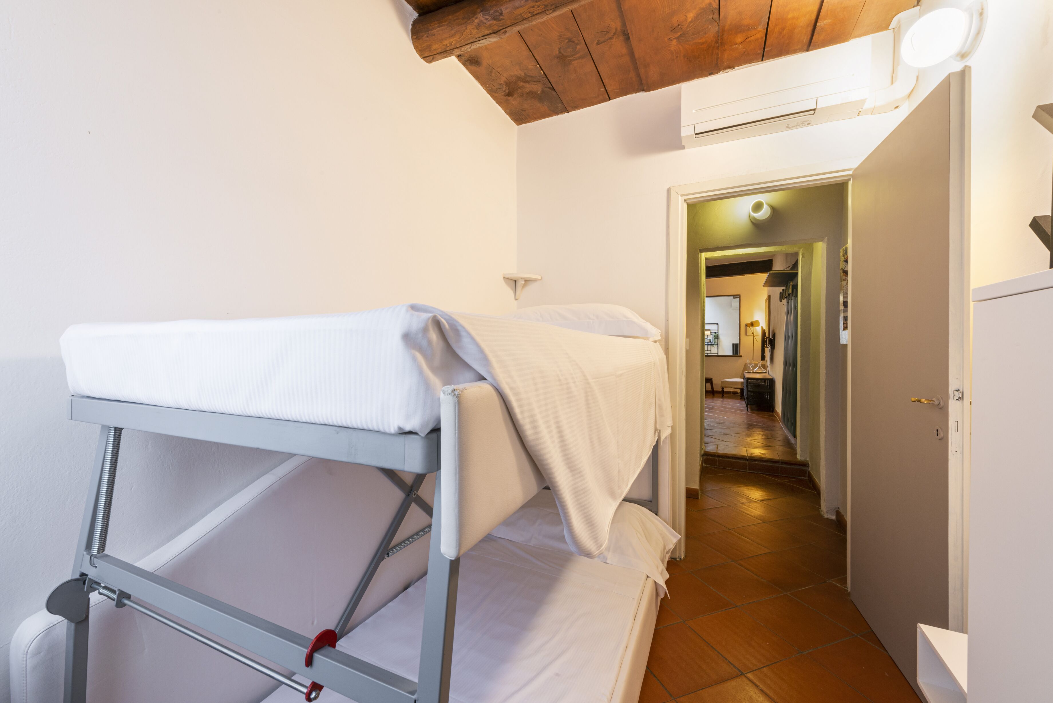 Una cama litera en una habitación con techo de madera y un pasillo que conduce a una zona de cocina.