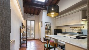 A kitchen with a large island, white cabinets, and a hanging light fixture. - Canacci by Mmega (Florence)