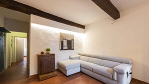 A corner living room with a sectional sofa, a small wooden cabinet, and a painting on the wall. - Canacci by Mmega (Florence)
