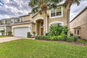 A residential house with a front garage, palm trees, and a well-maintained lawn.