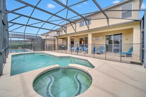 An indoor swimming pool with a glass ceiling, blue lounge chairs, and a covered patio area.