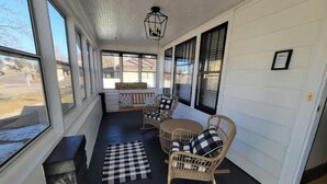 A covered porch with wicker rocking chairs and a table, large windows, and a sign reading "The Porch". - SPACIOUS BUNGALOW- 20min to WI Dells/Devils Lake (Portage)