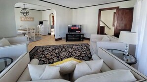 A modern living room with a sofa, a TV, and a dining area. - SPACIOUS BUNGALOW- 20min to WI Dells/Devils Lake (Portage)