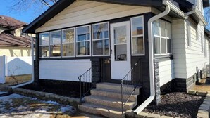 A two-story house with a garage, a front porch, and a small front yard. - SPACIOUS BUNGALOW- 20min to WI Dells/Devils Lake (Portage)