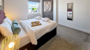 A modern bedroom with a bed, a window, and a view of the city. - Margaret's Loft by Fortuna Property Portfolio, The Margaret's Loft Apartment (Cheltenham)