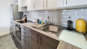 A modern kitchen with white cabinets, a stainless steel sink, and a wooden countertop. - Margaret's Loft by Fortuna Property Portfolio, The Margaret's Loft Apartment (Cheltenham)