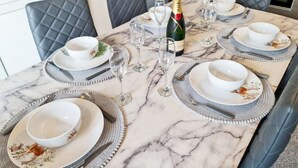 A dining table set for four with white plates, silverware, and wine glasses. - Margaret's Loft by Fortuna Property Portfolio, The Margaret's Loft Apartment (Cheltenham)
