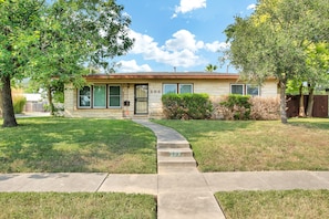 A single-story house with a number 203 on the door, a front yard, and a sidewalk leading to the entrance.