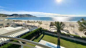 A coastal view with a beach, palm trees, and a clear sky.
