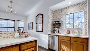 Une cuisine avec des meubles en bois, un lave-vaisselle et un plan de travail blanc.