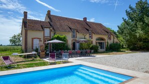Une maison à deux étages avec une piscine, un espace salon extérieur et un jardin.