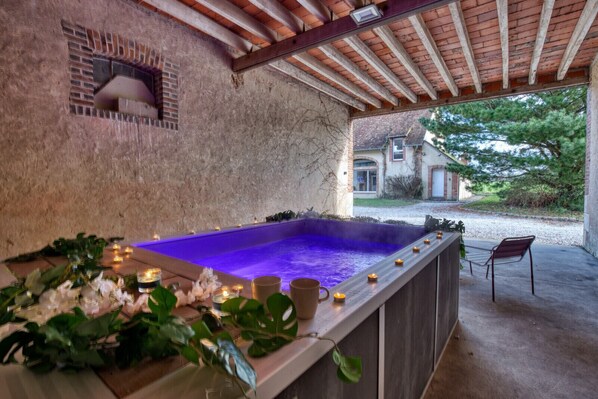 Un área de spa con jacuzzi, velas y plantas.