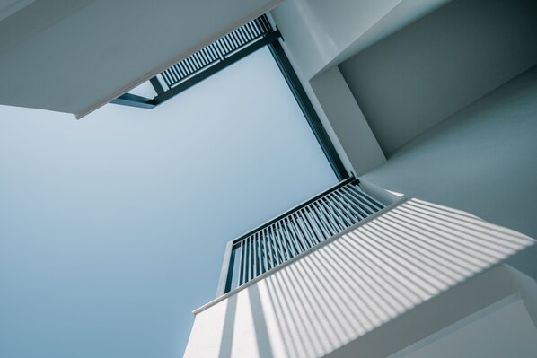 A modern architectural structure with a geometric design, featuring a prominent overhang and a metal railing.