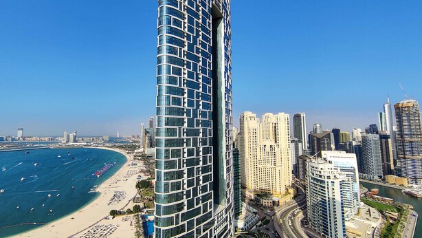 Un hôtel de grande hauteur à la façade incurvée, offrant une vue sur la plage et le paysage urbain.