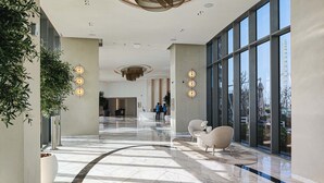 Un hall d’entrée spacieux doté d’un sol en marbre, de grandes fenêtres et d’un éclairage moderne.