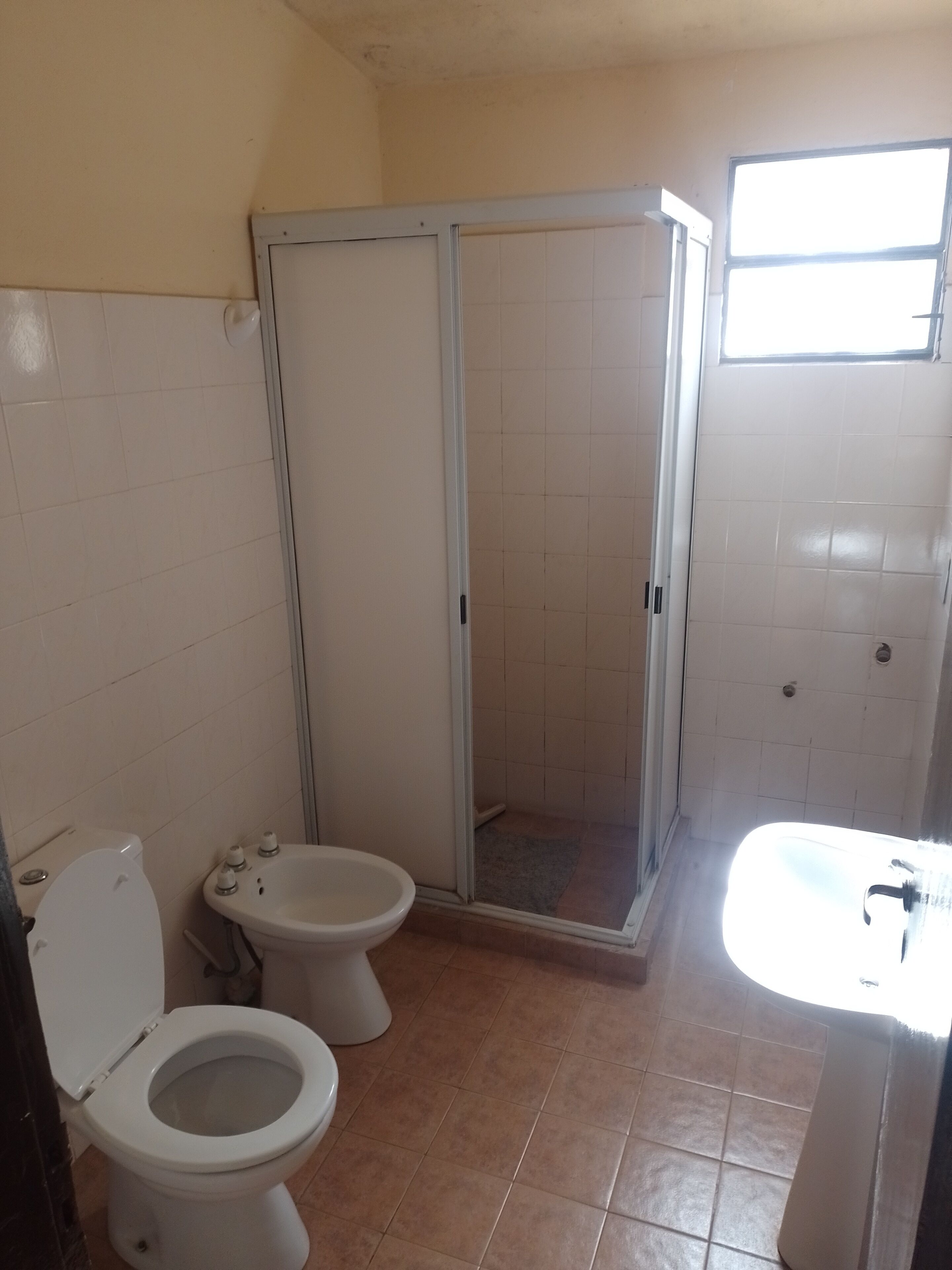 A bathroom with two toilets, a shower enclosure, and a sink.