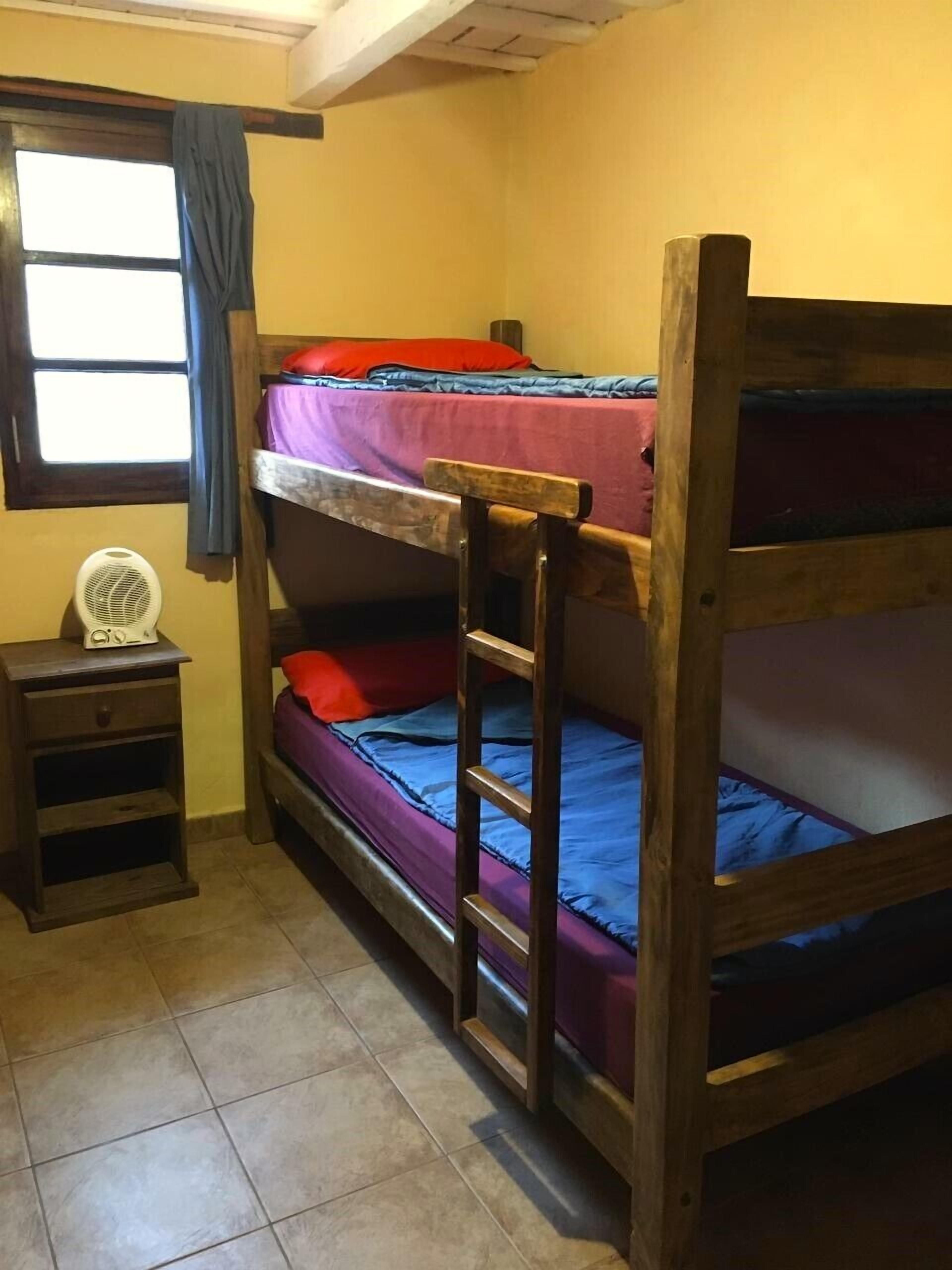 A bunk bed room with a small table and a fan.