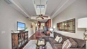 Un salon moderne avec un canapé, une table basse, un téléviseur et un ventilateur de plafond.
