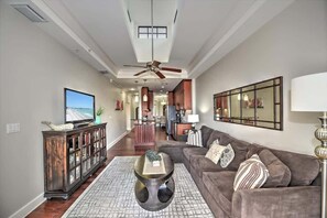 Un soggiorno moderno con divano, tavolino, televisore e ventilatore a soffitto.