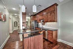 A modern kitchen with wooden cabinets, a black countertop, and pendant lighting.