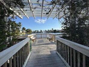 A wooden deck with railings, benches, and a pergola overhead.