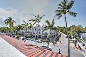 A hotel with a red and white striped awning, palm trees, and a street view with cars and pedestrians.