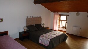 Un dormitorio con cama, mesitas de noche, una ventana y un radiador.