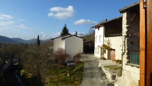 Un sendero estrecho que lleva a un edificio blanco, con un muro de piedra a un lado.