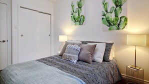 A bedroom with a bed, two wall-mounted paintings, a bedside lamp, and a door. - A charming little apartment in the lower town (Québec)