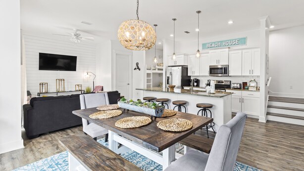 Een moderne keuken met witte kasten, een centraal eiland en een bord waarop 'BEACH HOUSE' staat.