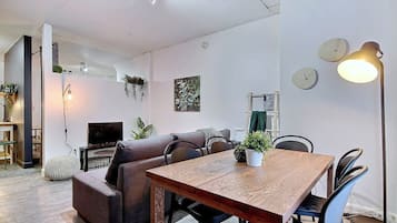 Un espacio moderno para vivir con una mesa de comedor de madera, un sofá y un televisor.