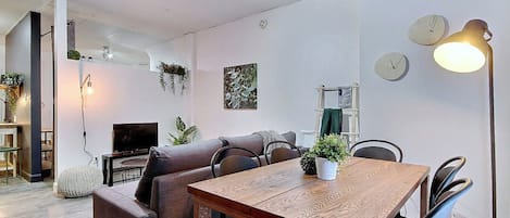 Un espace de vie moderne comprenant une table à manger en bois, un canapé et un téléviseur.