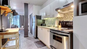 A modern kitchen with stainless steel appliances, a wooden table, and a checkered backsplash.
