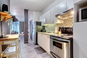Cocina moderna con electrodomésticos de acero inoxidable, una mesa de madera y un salpicadero a cuadros.