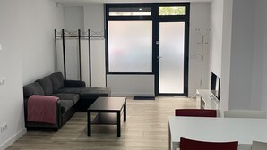 En moderne stue med sofa, sofabord og spiseområde med bord og stole.