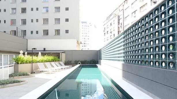 A rooftop swimming pool with lounge chairs and a view of surrounding buildings. - 123 Quarto - Sé (São Paulo)