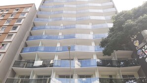 A high-rise building with multiple balconies and a modern architectural design. - 123 Quarto - Sé (São Paulo)