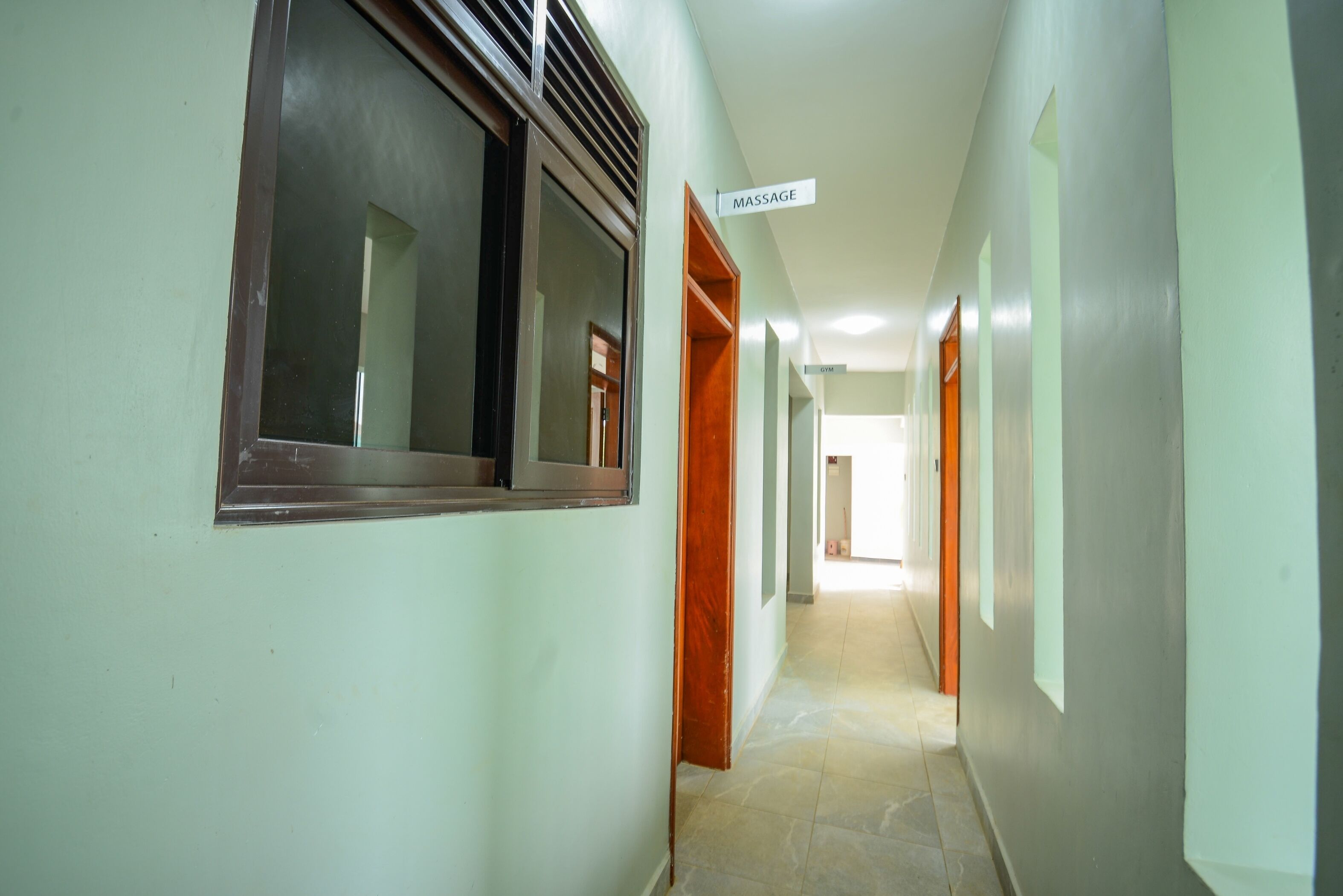 A hallway with a sign indicating a massage room, doors, and a tiled floor.