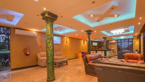 Un vestíbulo espacioso con techos altos, grandes columnas, asientos de cuero y una zona de bar.