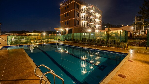 Un hotel con piscina, varios balcones y fachada bien iluminada.