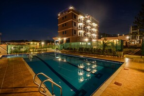 A hotel with a swimming pool, multiple balconies, and a well-lit exterior. - Mlex Hotel (Maya)