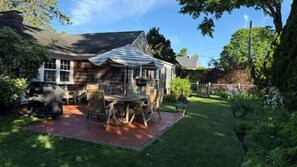 Ein Haus mit Terrasse, Grill und Garten.
